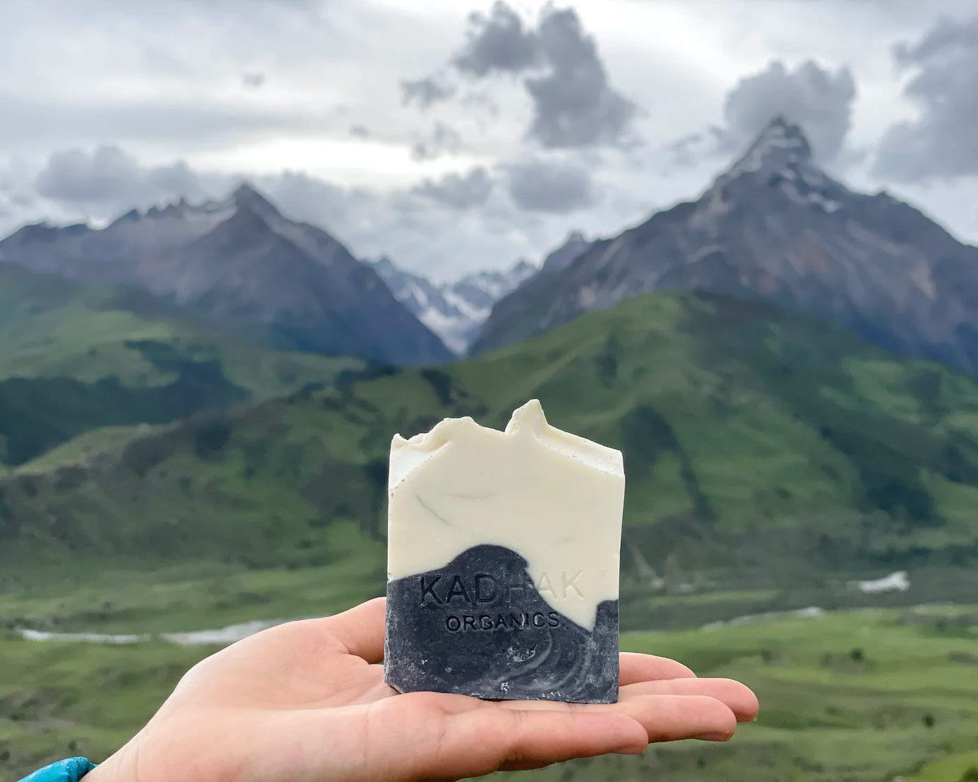 Bar of soap held in a hand with mountains in the background